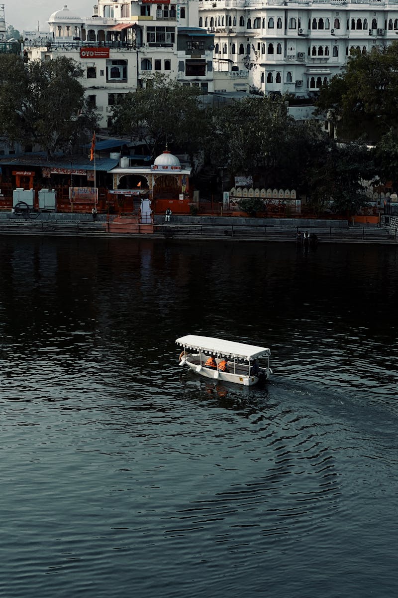 White boat navigating city lake surrounded by historic architecture.